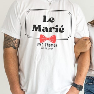K&ouml;nnte beinhalten: Wei&szlig;es T-Shirt mit einem schwarz-wei&szlig;en Etikett, auf dem "Le Mari&eacute;" steht, darunter ein roter Fliege. Das Etikett enth&auml;lt auch den Text "EVG Thomas 06.08.2024".