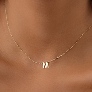 May include: A gold chain necklace with a small letter "M" pendant.