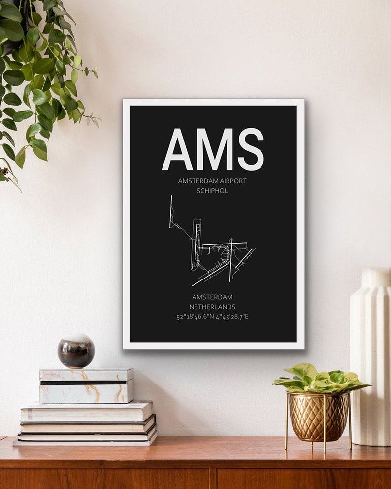 May include: A black and white airport map print with the text "AMS Amsterdam Airport Schiphol Amsterdam Netherlands 52&deg;18&prime;46.6&Prime;N 4&deg;45&prime;28.7"E".