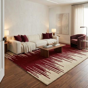 Könnte beinhalten: Ein modernes Wohnzimmer mit einem cremefarbenen Ecksofa und weinroten Kissen. Ein rechteckiger Couchtisch steht auf einem großen Teppich mit einem weinroten und cremefarbenen abstrakten Design. Ein weinroter Sessel und ein Beistelltisch vervollständigen den Raum.