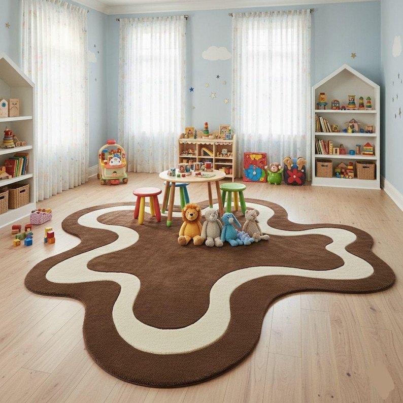 May include: A child's playroom with a brown and cream-colored rug shaped like a winding road. The room features white bookshelves, a small table with colorful stools, and various toys. Plush animals sit on the rug.