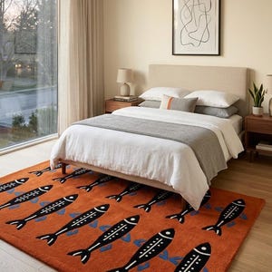 Könnte beinhalten: Ein orangefarbener Teppich mit einem sich wiederholenden Muster aus schwarzen Fischen mit weißen und blauen Akzenten. Der Teppich befindet sich in einem Schlafzimmer mit Bett, Nachttischen und Fenster.