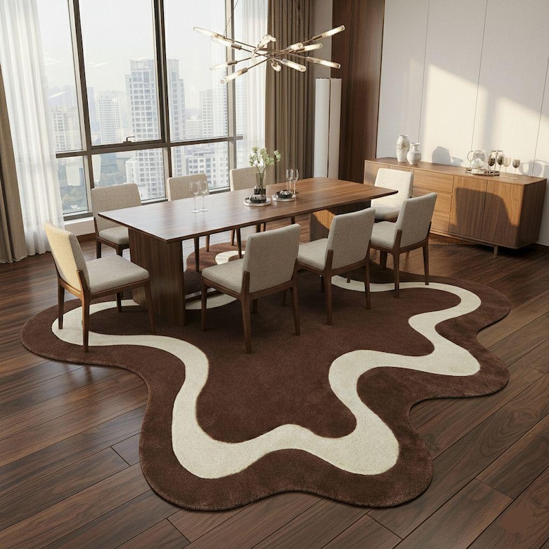 May include: A modern dining room set with a large wooden table and eight beige upholstered chairs. A unique brown rug with a cream-colored wavy design sits beneath the table. The room has large windows and a city view.