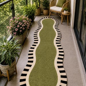 May include: An elongated, wavy-edged runner rug featuring a solid olive green center. The rug is bordered by a thick cream-colored band, which is further accented by a repeating pattern of short, vertical black stripes along the outer perimeter.