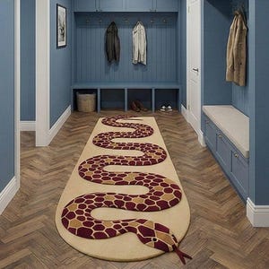 May include: A beige, snake-shaped rug with a detailed pattern in burgundy and tan. The rug is placed on a wooden floor in a hallway, with blue walls and built-in storage.
