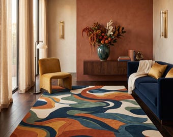 May include: A rectangular area rug featuring a fluid, abstract pattern of overlapping organic shapes in shades of deep navy blue, burnt orange, muted sage green, and cream, covering the floor in a living room with a dark wood floor.