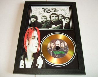 May include: Framed artwork featuring the band My Chemical Romance. The frame holds a photo of the band, a gold-colored CD, and a black and white image of a band member with red hair. The band's name is visible on the CD.