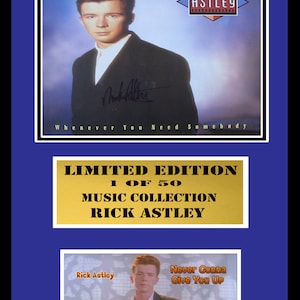 May include: A framed, limited edition print of a Rick Astley album cover. The album cover features a photo of Rick Astley in a black suit jacket. The album title is "Whenever You Need Somebody". The print is numbered 1 of 50 and includes a signature. The bottom of the frame features a smaller image of Rick Astley from the music video for "Never Gonna Give You Up".