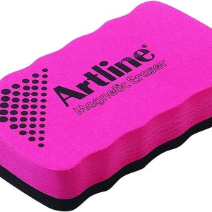 Puede incluir: Una goma magn&eacute;tica rosa con el texto "Artline Magnetic Eraser" impreso en ella. La goma tiene un borde negro y una superficie texturizada.
