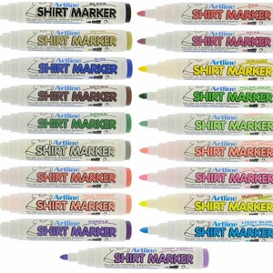 Può includere: Un set di 15 pennarelli per tessuti in vari colori, tra cui nero, beige, marrone, verde, grigio, arancione, arancio chiaro, viola, rosso, rosa, giallo, giallo verde, verde fluorescente, arancione fluorescente, rosa fluorescente e blu chiaro. I pennarelli sono etichettati "Artline Shirt Marker" e sono progettati per l'uso su t-shirt, felpe, jeans e altri tessuti di cotone.