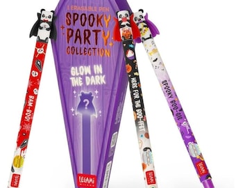 Puede incluir: Una caja morada con forma de ataúd etiquetada como Spooky Party Collection Glow in the Dark con tres bolígrafos borrables. Los bolígrafos tienen adornos de panda con capas y patrones de calaveras, calabazas y esqueletos con textos.