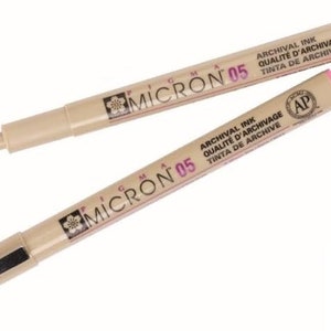 May include: Two brown and beige Micron 05 pens with black caps and green and pink caps. The pens have the text "Micron 05" and "Archival Ink Qualite d'Archive Tinta de Archive" printed on them. The pens are made in Japan.