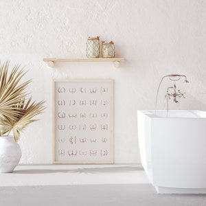 May include: A white bathroom with a freestanding bathtub, a wooden shelf with two glass jars, and a framed print with a pattern of abstract symbols. The print is in a light wood frame.