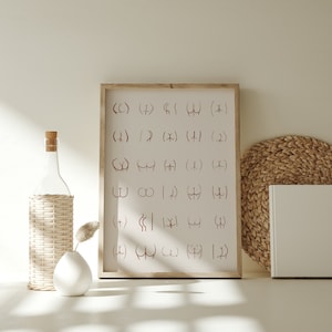 May include: A framed print with a white background and brown lines forming various shapes. The print is hanging on a white wall with a wicker bottle holder, a clear glass bottle, and a white vase with a dried plant stem.