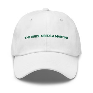 May include: White baseball cap with the text "THE BRIDE NEEDS A MARTINI" embroidered in green.