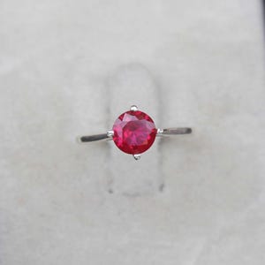 May include: A silver ring set with a red ruby gemstone.