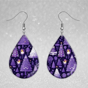 May include: Purple and white teardrop-shaped earrings with a winter forest pattern. The earrings feature small trees, stars, and a whimsical character.