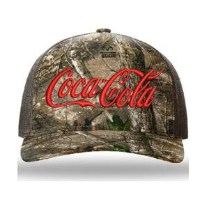 May include: A brown and green camouflage trucker hat with a red embroidered Coca-Cola logo. The hat has a black mesh back and a white "Wilderness Edge" logo.