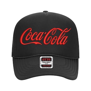 May include: Black trucker hat with a red embroidered Coca-Cola logo. The hat has a black mesh back and a black foam front. The hat also has a small black and white label that says "OTTO WORLD FAMOUS FOAM FRONT CAP TRUCKER DURABLE SNAP CLOSURE".