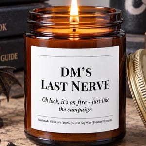 Puede incluir: Una vela encendida en un frasco de vidrio ámbar con una etiqueta blanca que dice DM'S LAST NERVE. Oh look, it's on fire - just like the campaign. Handmade With Love | 100% Natural Soy Wax | KaliBayElements. La vela tiene una tapa dorada.