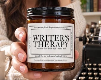 May include: A brown glass candle jar with a black lid and a white rectangular label. The label features the text WRITER'S THERAPY, hand-poured for the keeper of unfinished drafts, draft, delete, repeat, for writers who bleed ink, a candle for storytellers and midnight typers, Handmade USA, 100% Natural Soy Wax, KaliBayElements.