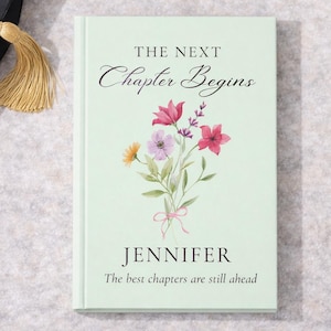 May include: A light green book with the text "THE NEXT Chapter Begins" and "JENNIFER". The book cover features a watercolor floral bouquet with pink, purple, and yellow flowers. The text "The best chapters are still ahead" is also on the cover.