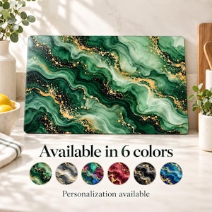 May include: A rectangular cutting board featuring a green and white marble pattern with gold flecks. Below the board, the text reads Available in 6 colors, followed by six circular swatches in green, gray, purple, red, black, and blue, and the text Personalization available.