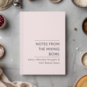 May include: A cookbook titled "Notes From The Mixing Bowl" with the text "Kelly's Whisked Thoughts & Half-Baked Ideas" is surrounded by baking ingredients. Ingredients include flour, sugar, and beans. The book is light pink.