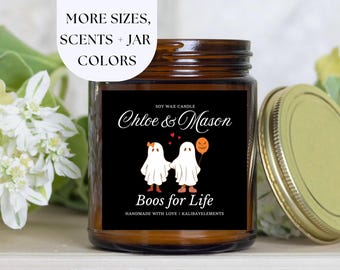 May include: A soy wax candle in a brown glass jar with a gold lid. The black label features the text "Chloe & Mason" and two ghost illustrations holding hands, with the words "Boos for Life". The image also includes the text "More Sizes, Scents + Jar Colors".