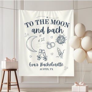 Puede incluir: Un telón de fondo color crema con el texto "TO THE MOON and bach" e ilustraciones de una luna, estrellas, anillos, bola de discoteca, copas de champán y un cohete. También se incluye el texto "Eva's Bachelorette" y "AUSTIN, TX".