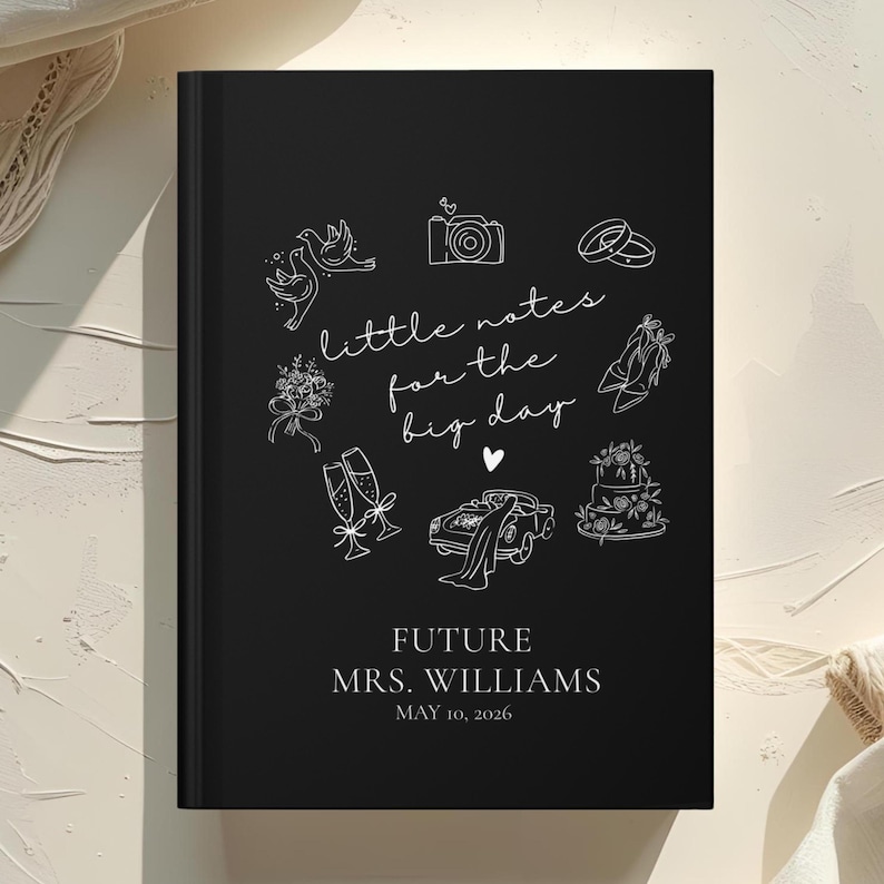 May include: A black journal with white line art illustrations of wedding-related icons, including doves, a camera, rings, and a cake. The text "little notes for the big day" is written in cursive. The journal is personalized with the text "FUTURE MRS. WILLIAMS MAY 10, 2026."