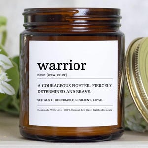 May include: A brown glass candle jar with a white label that reads "warrior" and its definition. The label also includes the text "Handmade With Love | 100% Coconut Soy Wax | KalillayElements".