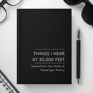May include: A black journal with the text "THINGS I HEAR AT 30,000 FEET" and "Samantha's Sky Notes & Passenger Poetry" is displayed. A black pen, eyeglasses, and sunglasses are also visible. The journal is on a white surface.
