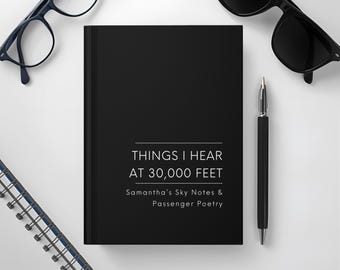 May include: A black journal with the text "THINGS I HEAR AT 30,000 FEET" and "Samantha's Sky Notes & Passenger Poetry" is displayed. A black pen, spectacles, and sunglasses are also visible. The journal is on a white surface.