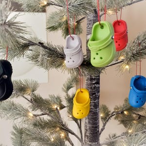May include: A Christmas tree decorated with colorful plastic ornaments shaped like clogs. The ornaments are in various colors, including red, green, blue, yellow, and black.