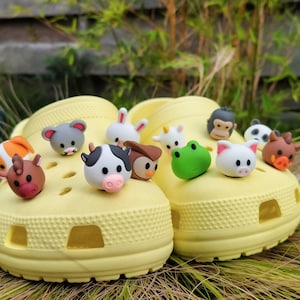 May include: A pair of bright yellow foam clogs decorated with various colorful animal-shaped charms. The charms include a cow, frog, pig, monkey, panda, owl, rabbit, horse, and other small creatures inserted into the ventilation holes.