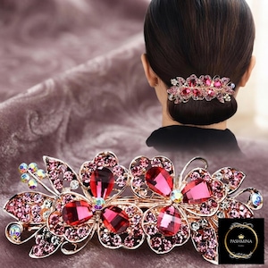 Peut inclure: Une barrette à cheveux décorative au motif floral avec un filigrane doré, ornée de nombreuses petites pierres roses et de plus grandes pierres facettées en forme de goutte d'un rose profond. L'accessoire est présenté seul et porté.