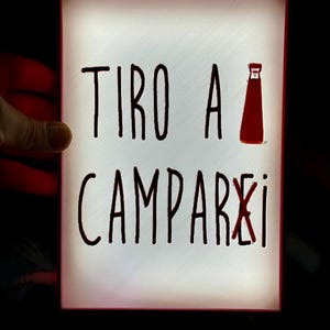 Peut inclure: Une enseigne lumineuse blanche avec une inscription noire qui dit "TIRO A CAMPARI" avec une silhouette rouge d'une bouteille de Campari.