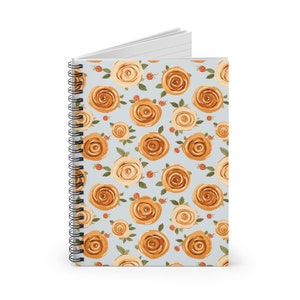 May include: A spiral bound notebook with a light blue cover featuring a repeating pattern of orange and yellow roses.