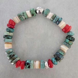 Puede incluir: Una pulsera de cuentas coloridas con cuentas turquesas, rojas y blancas, y una cuenta plateada. El diseño de la pulsera incorpora varias formas y texturas, creando un accesorio vibrante. Esta pulsera es una gran adición a cualquier colección de joyas.