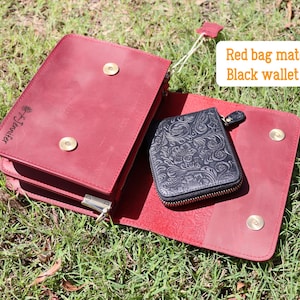 May include: A red leather bag with a flap closure and gold accents. The bag has a small black leather wallet with a floral design inside. The bag has the text "The Journey" embossed on the front.