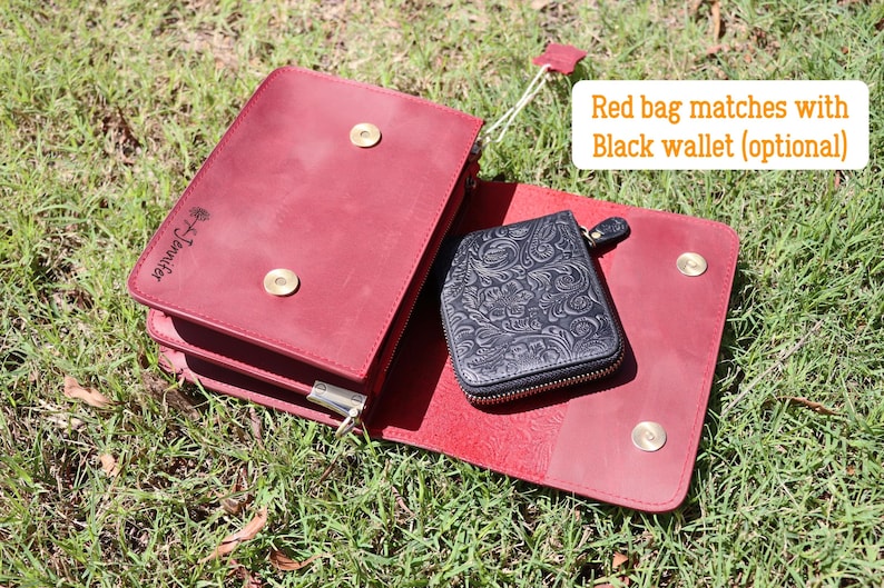 May include: A red leather bag with a flap closure and gold accents. The bag has a small black leather wallet with a floral design inside. The bag has the text "The Journey" embossed on the front.