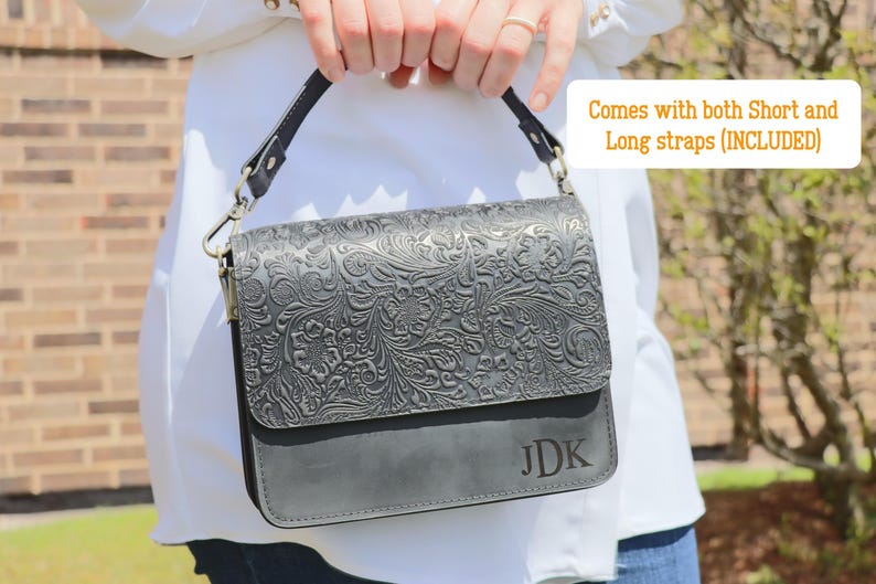 May include: A black leather handbag with an embossed floral design. The bag has a short strap and a long strap, and the initials "JDK" are embossed on the front.