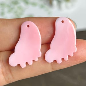Può includere: Due ciondoli a forma di farfalla in plastica rosa con un foro nella parte superiore per appenderli.