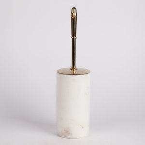 May include: White marble toilet brush holder with a gold metal handle.