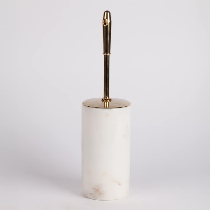 May include: White marble toilet brush holder with a gold metal handle.