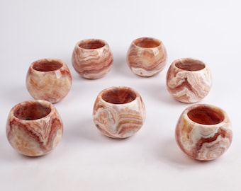 Puede incluir: Juego de siete pequeñas copas redondas de ónix blanco y rojo. Las copas tienen un patrón de remolino y son perfectas para servir bebidas pequeñas o como piezas decorativas.