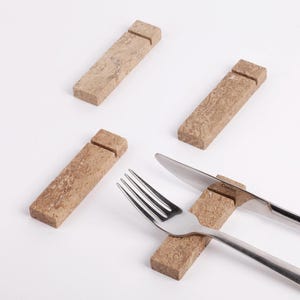 Può includere: Quattro porta carte rettangolari di colore marrone con venature di marmo con una fessura per una carta. Una forchetta e un coltello sono posizionati su un supporto, con il nome del marchio del coltello "Camino" visibile.