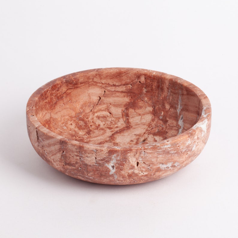 May include: A round, brown marble bowl with a white marbled pattern. The bowl is made of natural stone and has a rustic, handmade look.