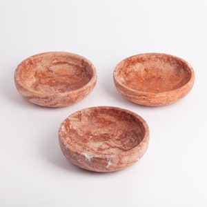 May include: Three small, round, brown and white marble bowls. The bowls are made of a natural stone with a swirling pattern.